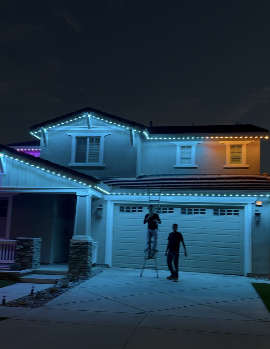 Teal and warm white permanent lighting on a two-story Queen Creek home at night