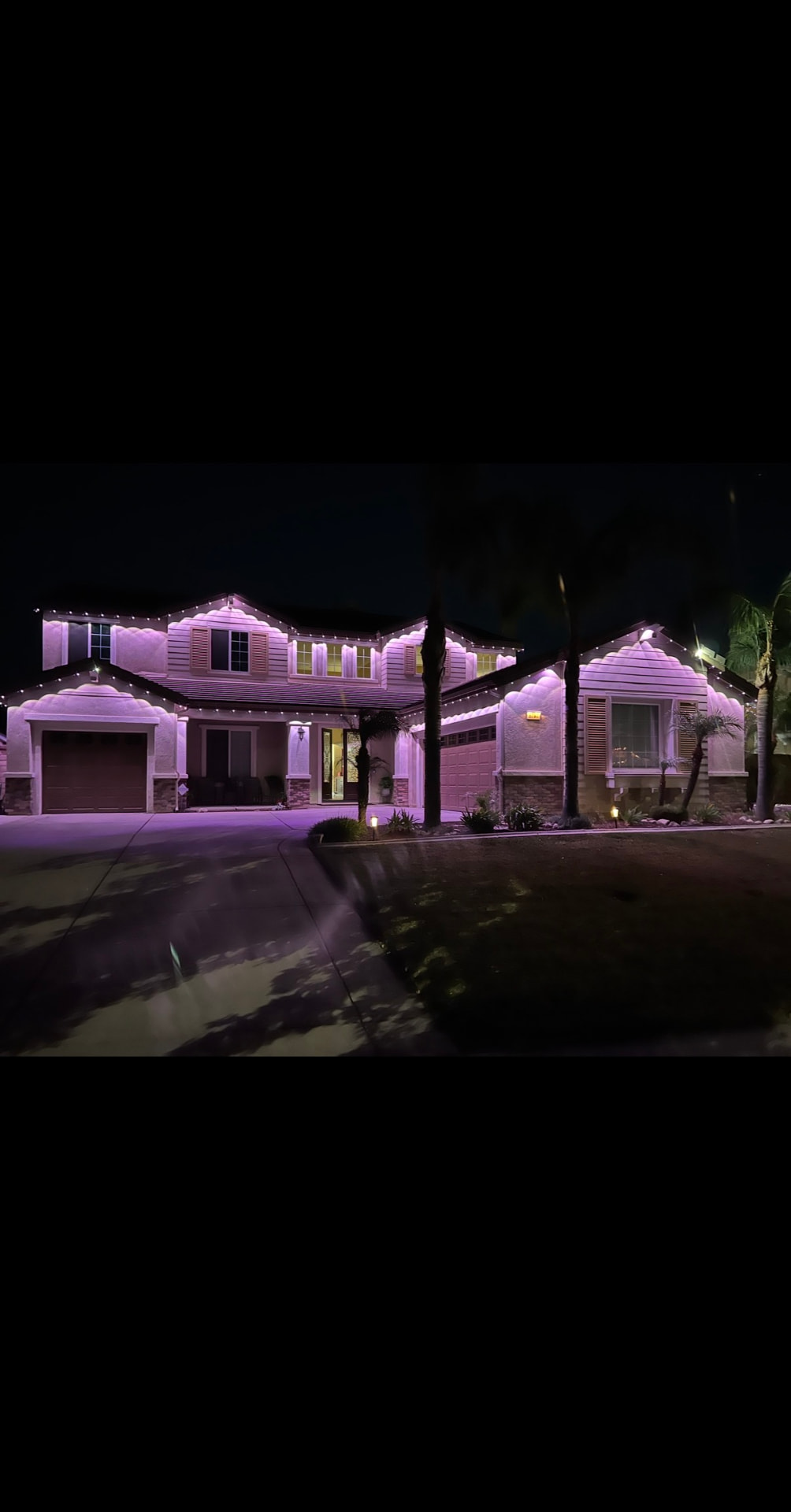Pink and purple permanent accent lighting on a two-story home at night